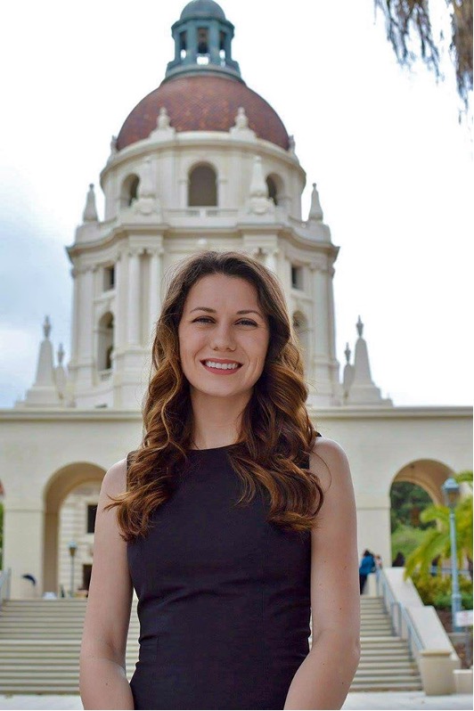 A woman standing in front of a building with a tower.