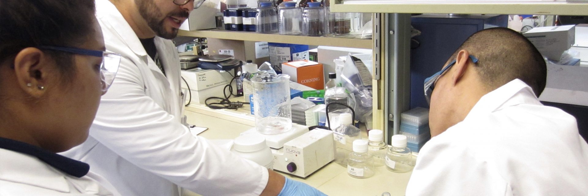 A person in lab coat working on equipment.