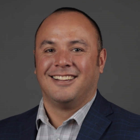 A man in a suit and tie smiling for the camera.