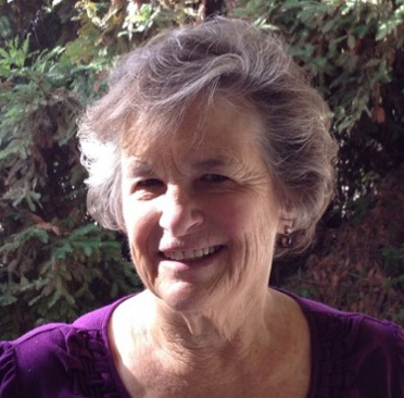 A woman in purple shirt smiling for the camera.