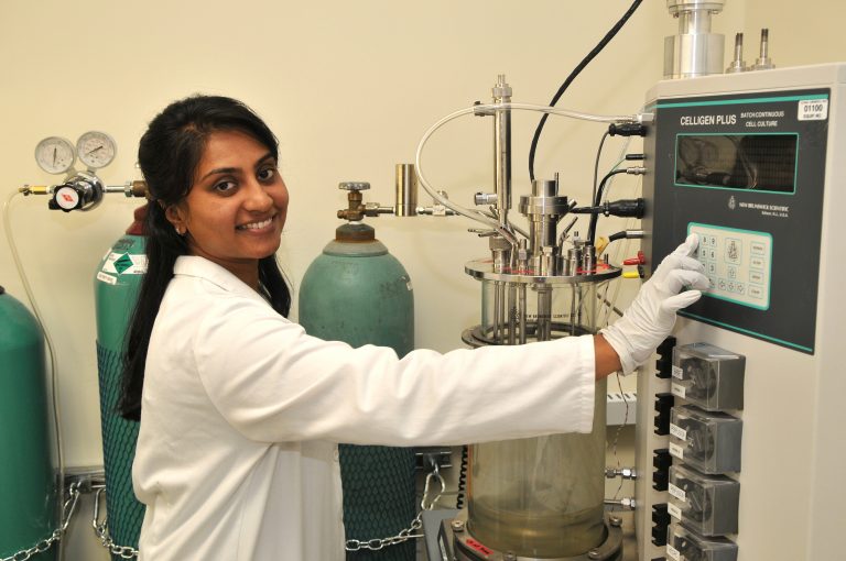 A woman in white lab coat and gloves working.