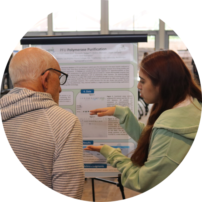 A woman pointing to a poster while standing next to an older man.