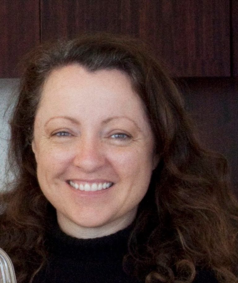 A woman with long hair smiling for the camera.